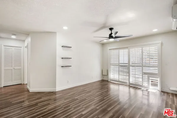 a view of an empty room with a window and wooden floor