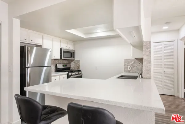 a kitchen with a refrigerator a stove a sink dishwasher with a dining table and chairs
