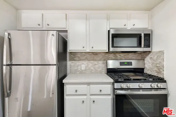 a kitchen with cabinets stainless steel appliances and a counter space