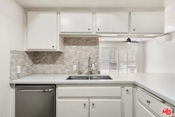 a kitchen with granite countertop a sink and a white cabinets