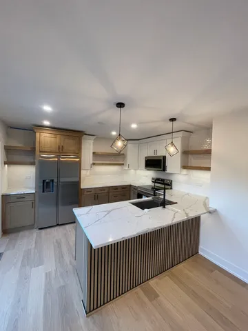 a kitchen with stainless steel appliances kitchen island granite countertop a stove a sink and a refrigerator