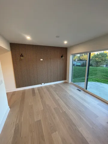 a view of an empty room with wooden floor and fence