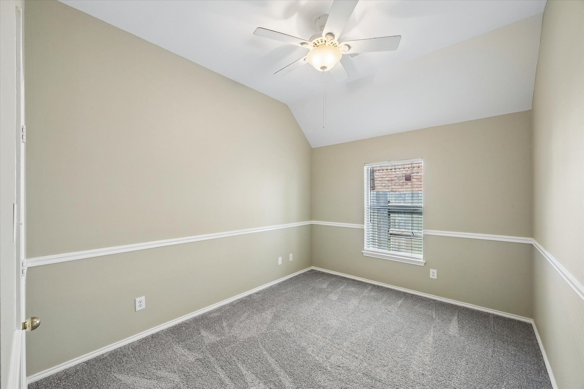 3118 Valley Court Manvel, TX 77578 - Photo 19 of 38 This room features neutral walls with a white chair rail, a vaulted ceiling with a ceiling fan, and a window with blinds, providing a cozy and bright space. The carpeted floor adds warmth and comfort.