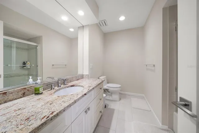 a bathroom with a granite countertop sink a toilet and a mirror