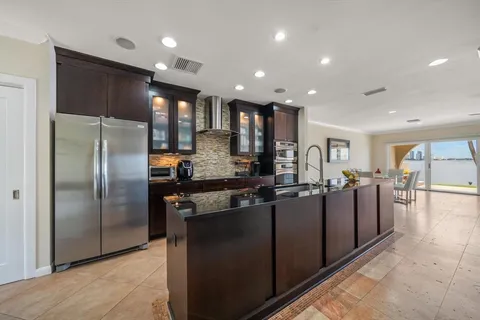 a kitchen with stainless steel appliances granite countertop a refrigerator a sink a stove and oven