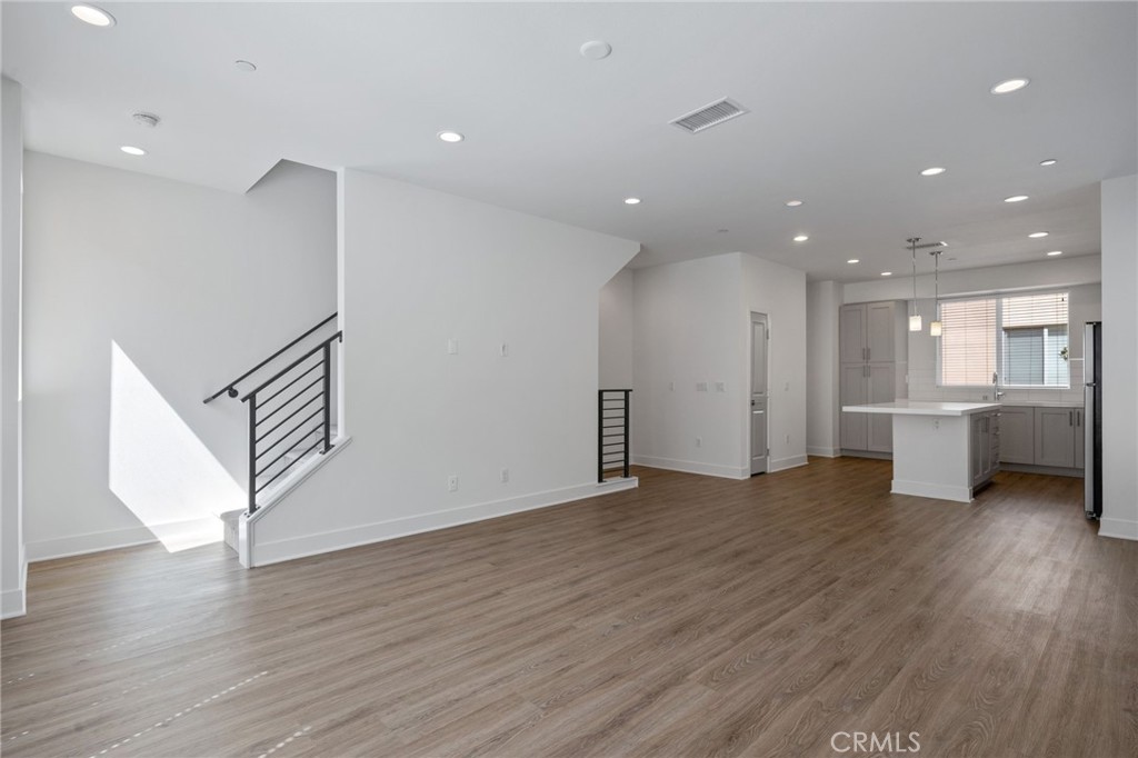 a view of a big room with wooden floors and kitchen view