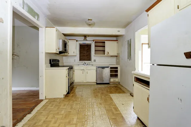 a view of kitchen with microwave a stove and white cabinets