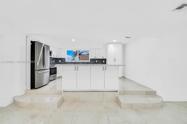 a kitchen with granite countertop white cabinets and stainless steel appliances