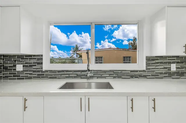 a view of a kitchen with kitchen island a sink wooden floor and a refrigerator in it