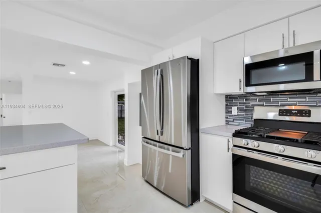 a view of a kitchen with kitchen island and stainless steel appliances