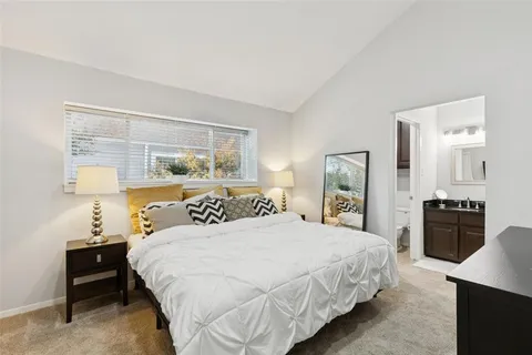 a bedroom with a large bed and a lamp on dresser