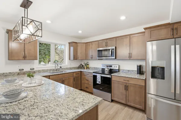 a kitchen with stainless steel appliances granite countertop a sink stove microwave and refrigerator