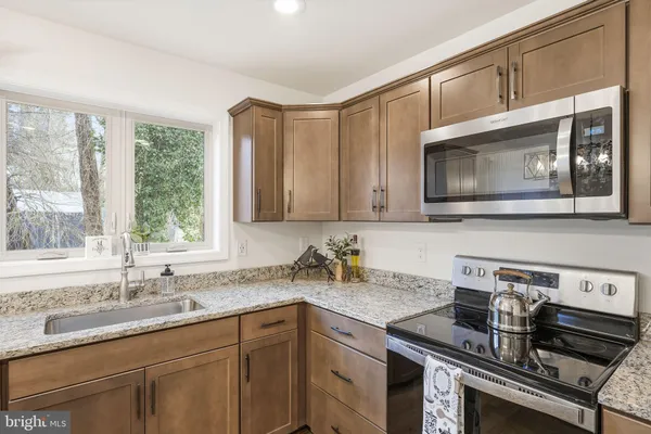 a kitchen with granite countertop a sink a stove and cabinets