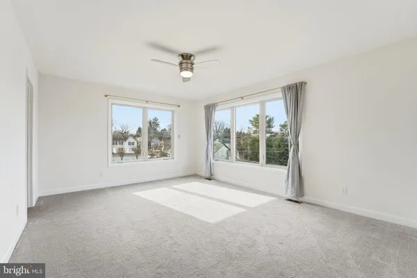 a view of a big room with windows and chandelier fan