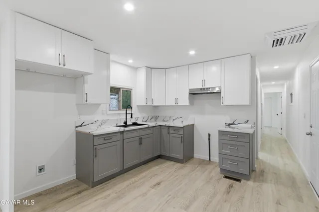 a kitchen with a sink cabinets and wooden floor