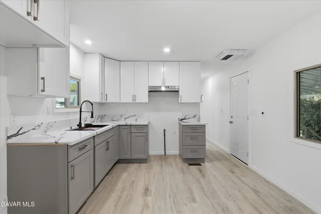 a kitchen with white cabinets stainless steel appliances a sink and a window