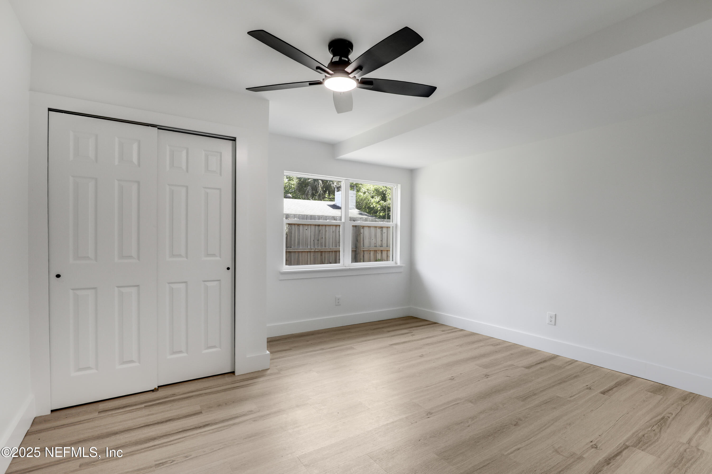 4630 Homestead Road Jacksonville, FL 32210 - Photo 17 of 45 an empty room with wooden floor ceiling fan and windows