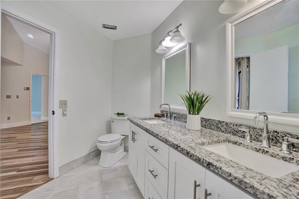 6698 Montego Bay Boulevard, Unit D Boca Raton, FL 33433 - Photo 20 of 44 a bathroom with a granite countertop sink a toilet and a mirror