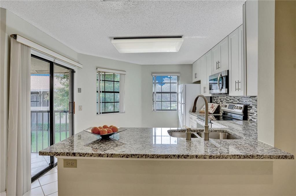 6698 Montego Bay Boulevard, Unit D Boca Raton, FL 33433 - Photo 2 of 44 a kitchen with granite countertop a sink a stove and a wooden floor