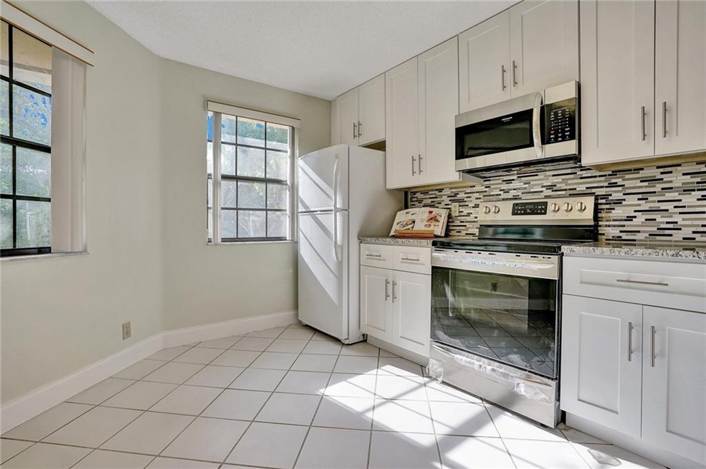 6698 Montego Bay Boulevard, Unit D Boca Raton, FL 33433 - Photo 3 of 44 a kitchen with stainless steel appliances a stove a microwave and a sink