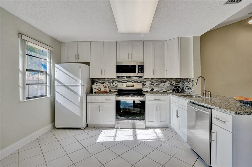6698 Montego Bay Boulevard, Unit D Boca Raton, FL 33433 - Photo 4 of 44 a kitchen with white cabinets and appliances