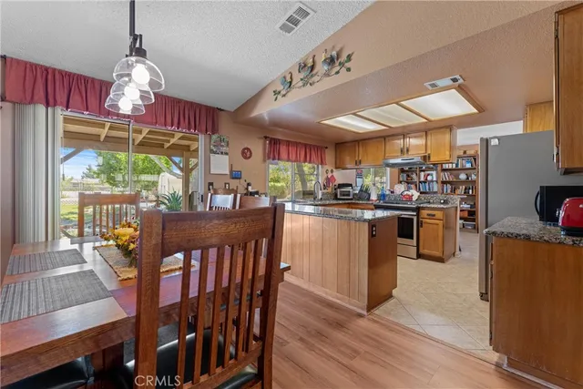 a kitchen with stainless steel appliances granite countertop a stove top oven a dining table and chairs with wooden floor