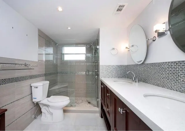 a bathroom with a double vanity sink mirror and toilet