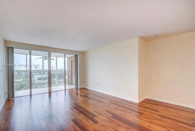 a view of an empty room with wooden floor and a window