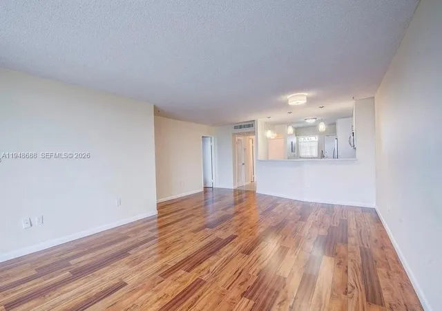 a view of a room with wooden floors and kitchen view