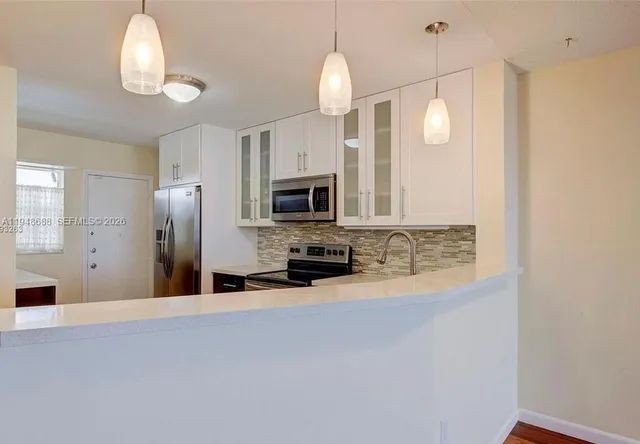 an empty room with kitchen view and a fireplace