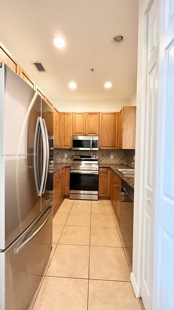 1475 Scilly Cay Lane, Unit 1475 Jupiter, FL 33458 - Photo 20 of 29 a kitchen with wooden cabinets and stainless steel appliances