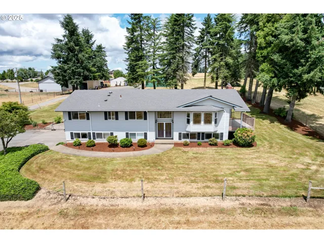 a view of a white house with a big yard and large trees