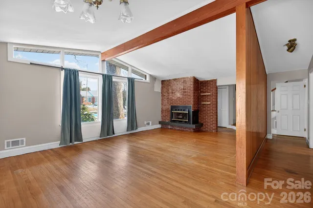 a view of an empty room with window and wooden floor