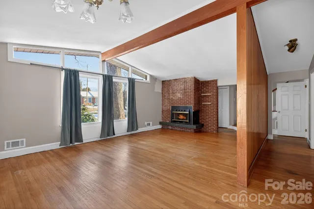 a view of an empty room with window and wooden floor