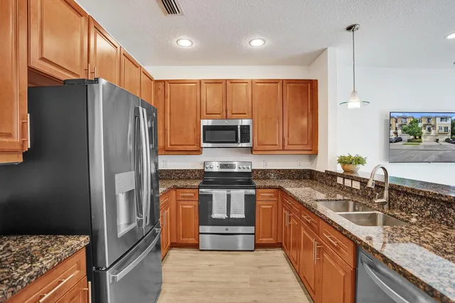 a kitchen with stainless steel appliances granite countertop a sink stove and refrigerator