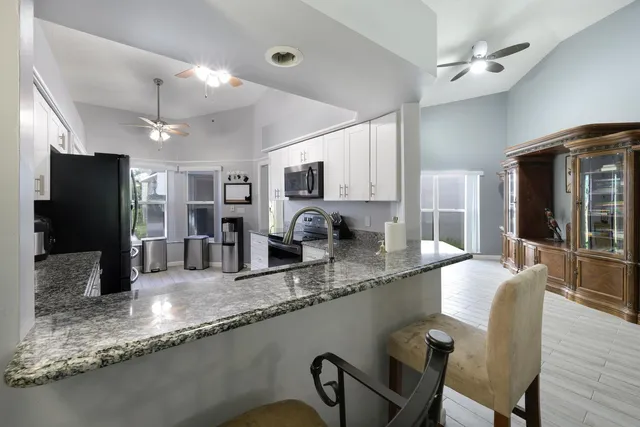 a large kitchen with granite countertop a large counter top appliances and cabinets