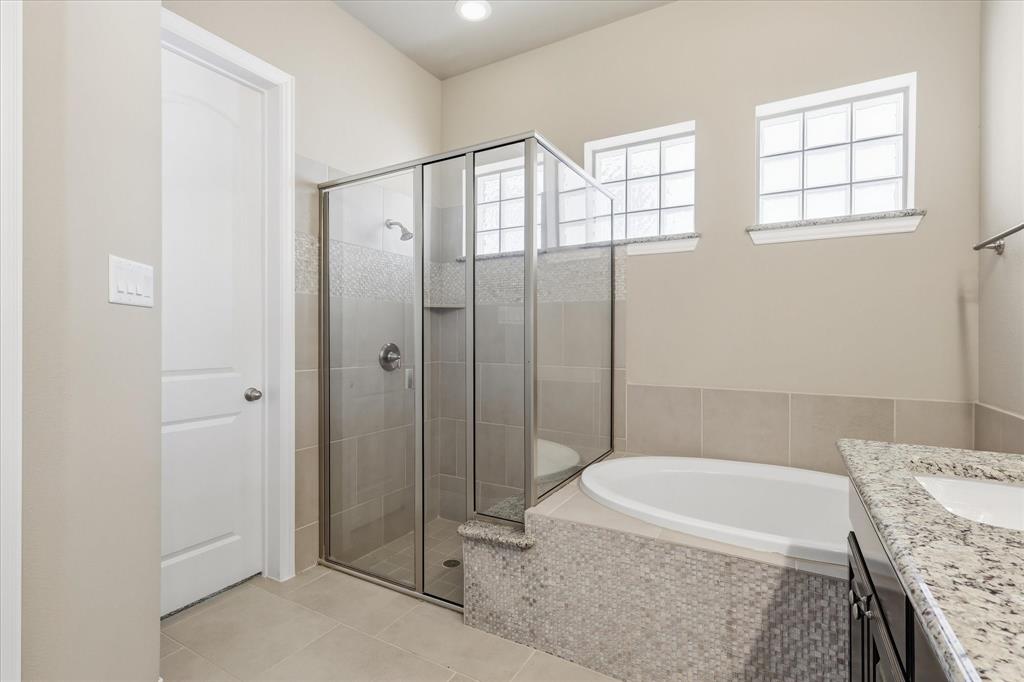 768 Huntingdon Street Coppell, TX 75019 - Photo 10 of 37 Well-appointed bathroom with a separate glass-enclosed shower, soaking tub, tile surround, and bright privacy windows.