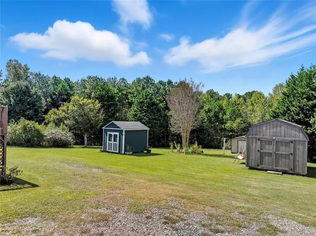 a view of a house with a big yard and large trees
