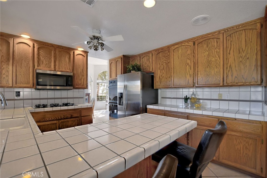 18032 Ohna Road Apple Valley, CA 92307 - Photo 18 of 65 a kitchen with stainless steel appliances a stove refrigerator sink and microwave