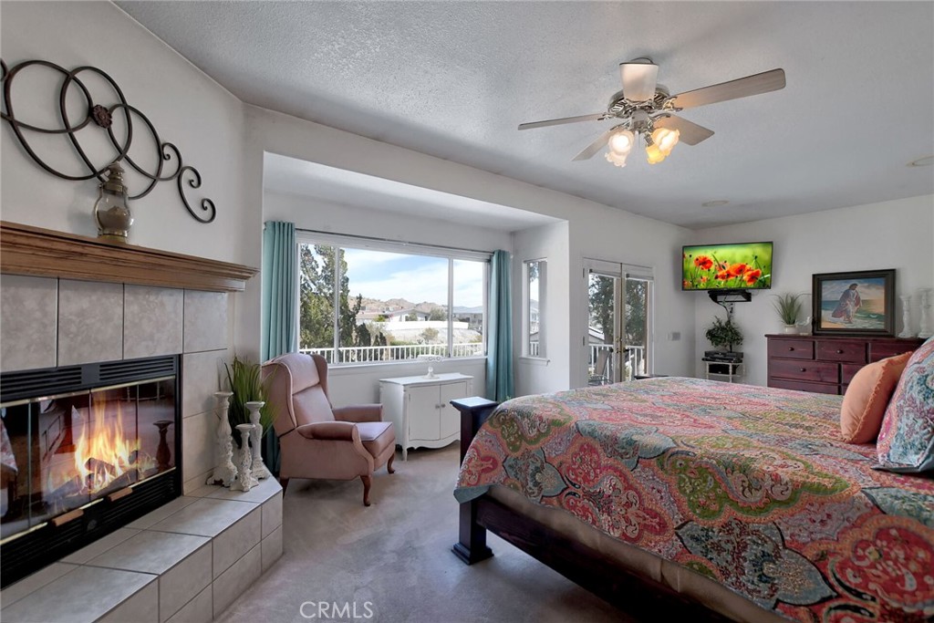 18032 Ohna Road Apple Valley, CA 92307 - Photo 33 of 65 a bedroom with a bed and a fireplace with a chandelier