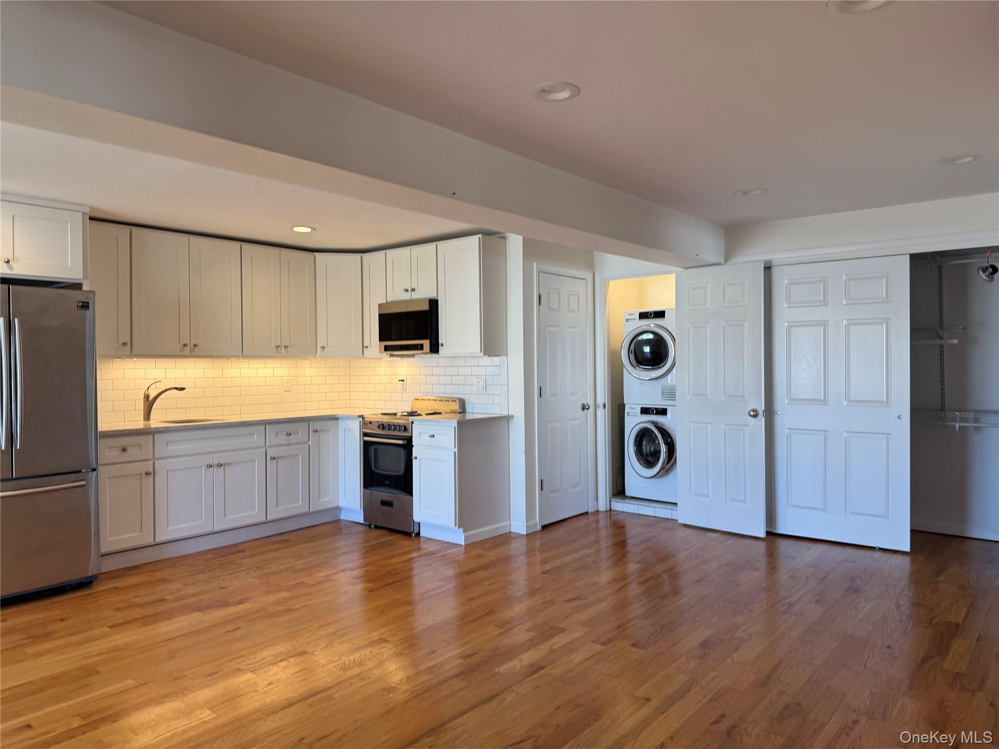 505 South Main Street Freeport, NY 11520 - Photo 3 of 10 Kitchen with appliances with stainless steel finishes, white cabinets, light wood finished floors, tasteful backsplash, and recessed lighting