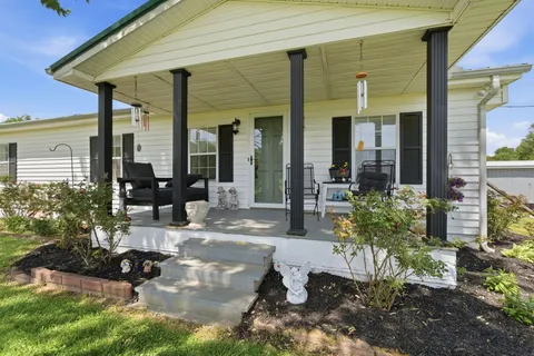 a view of a patio with table and chairs potted plants and floor to ceiling window