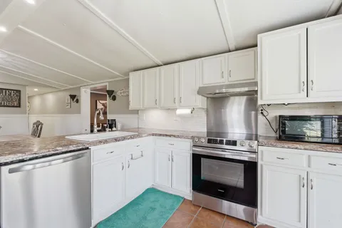 a kitchen with granite countertop a stove sink and cabinets