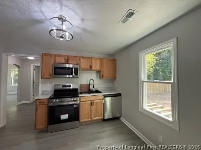 a kitchen with stainless steel appliances a stove a sink a microwave cabinets and a window