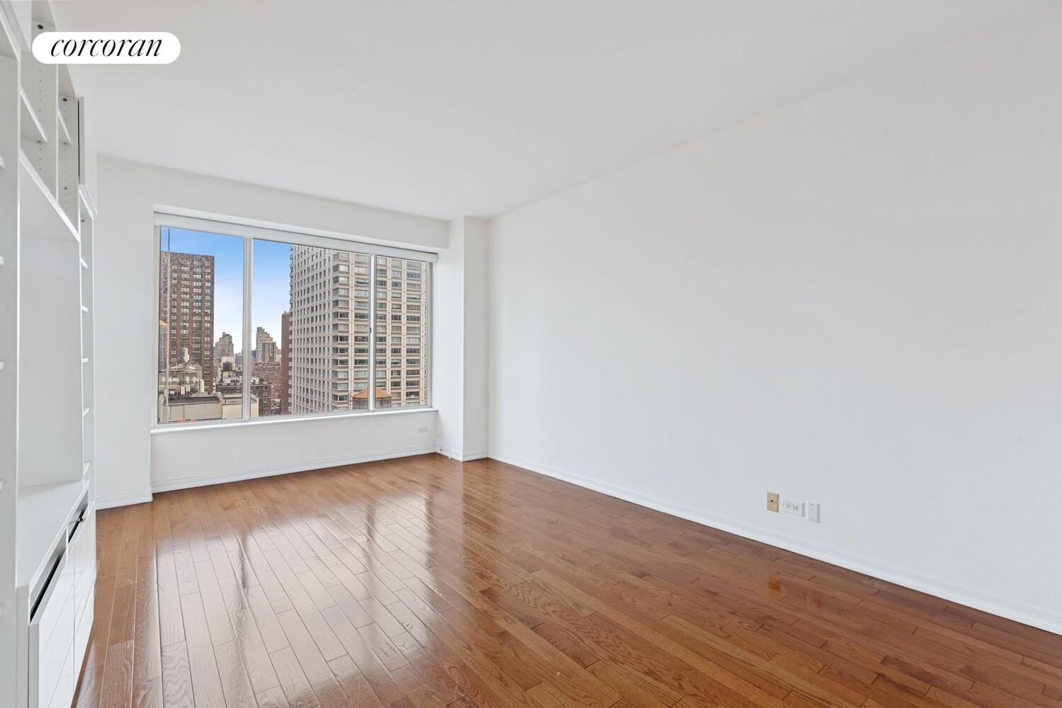 200 East 69th Street, Unit 21A Manhattan, NY 10021 - Photo 6 of 12 a view of an empty room with wooden floor and a window