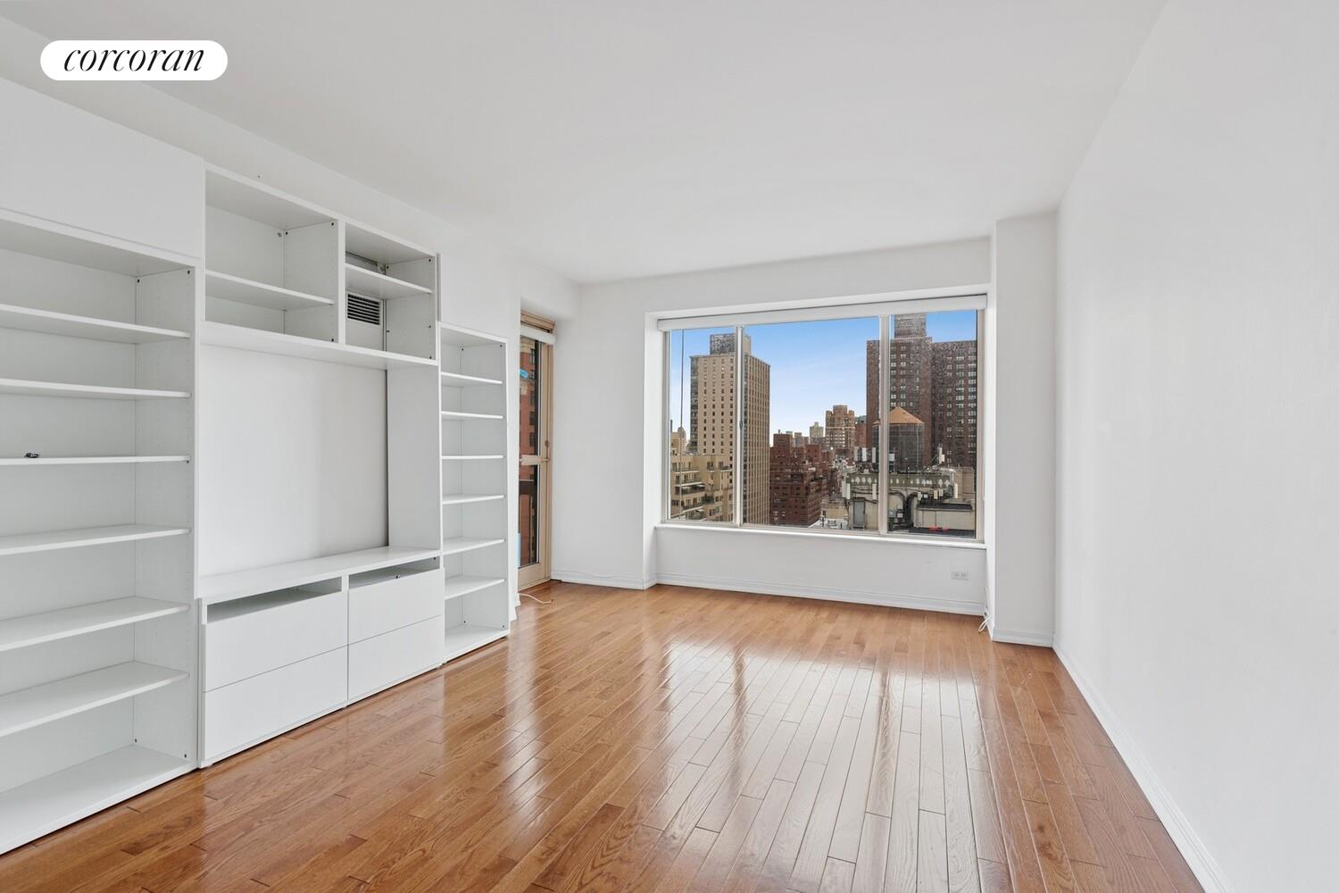 200 East 69th Street, Unit 21A Manhattan, NY 10021 - Photo 7 of 12 a view of an empty room with a window and wooden floor
