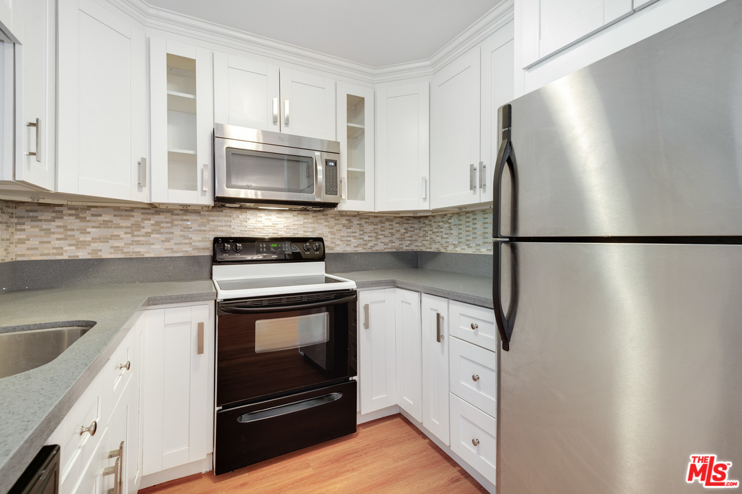 11750 Sunset Boulevard, Unit 123 Los Angeles, CA 90049 - Photo 11 of 31 a kitchen with stainless steel appliances white cabinets and a granite counter tops