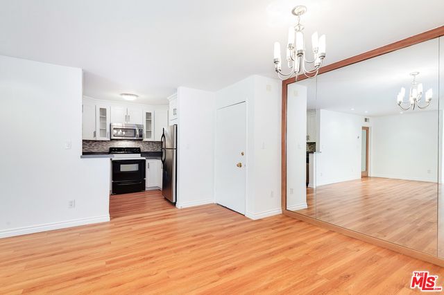 a view of a kitchen with stainless steel appliances granite countertop a refrigerator and a stove top oven