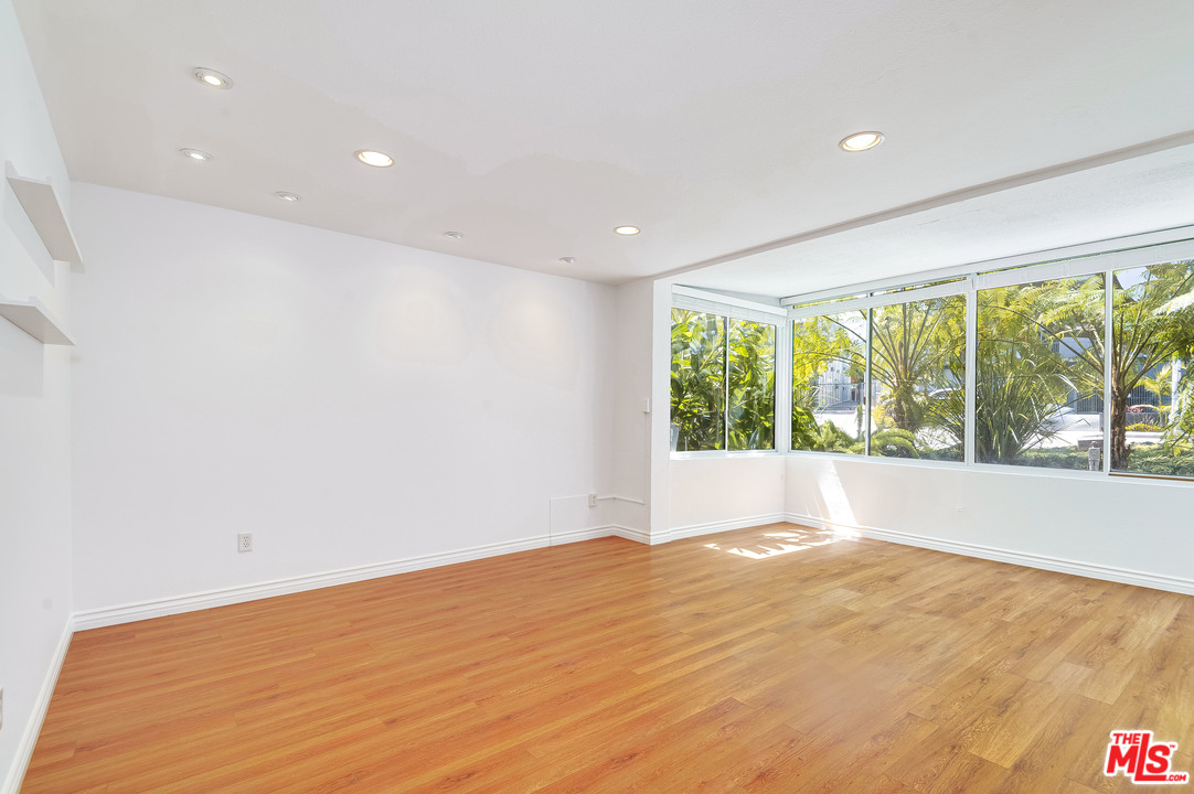 11750 Sunset Boulevard, Unit 123 Los Angeles, CA 90049 - Photo 9 of 31 a view of an empty room with wooden floor and a window