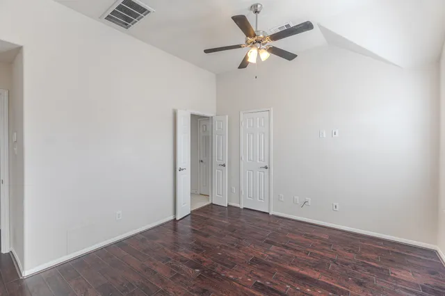 an empty room with wooden floor and ceiling fan